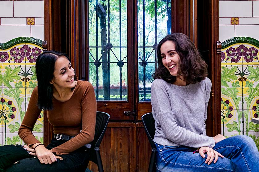Ana i Lucía assegudes d'esquenes es miren als ulls a una sala de la Granja Soldevila